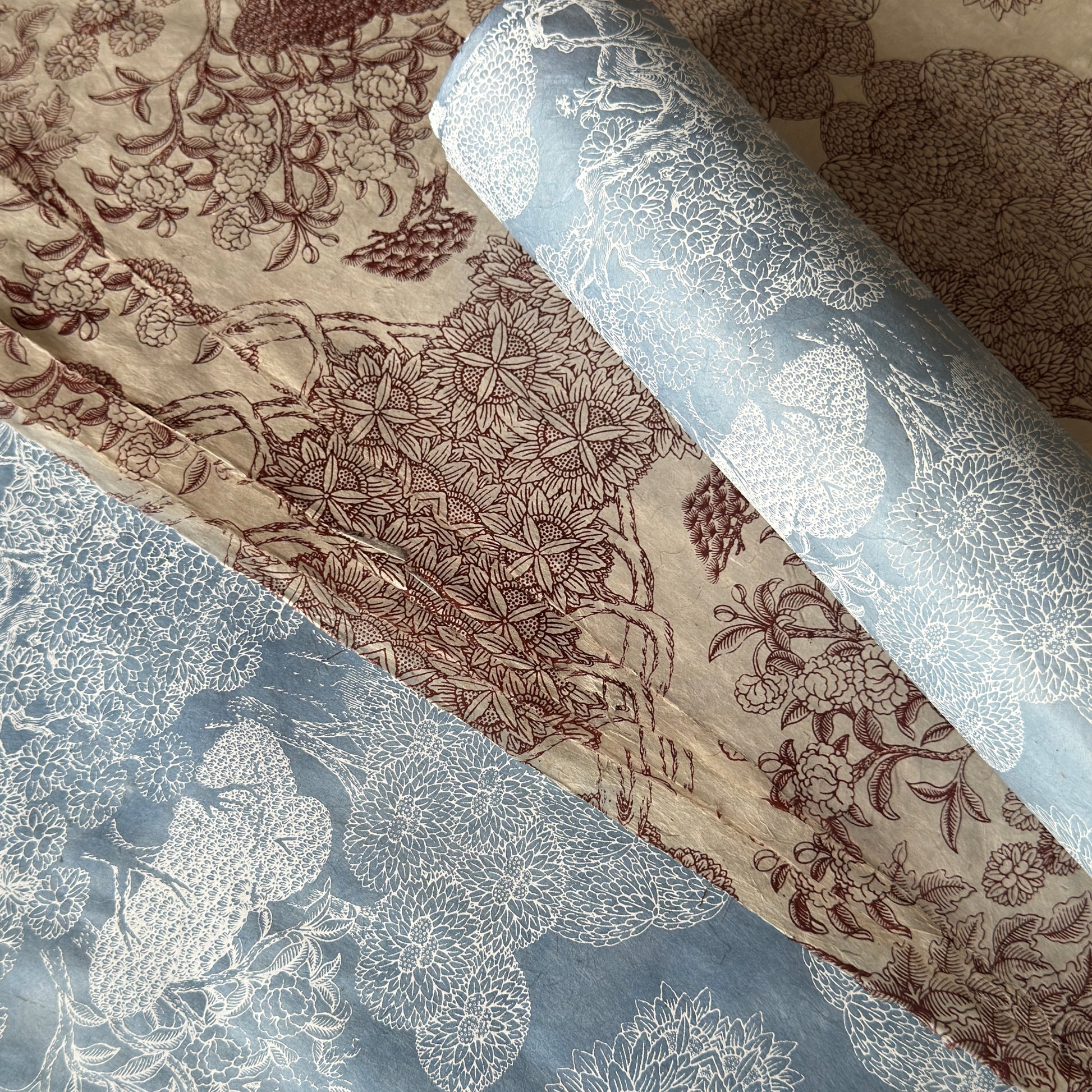 a sheet of Nepalese lokta paper in sky blue with a detailed pattern of trees and flowers screen printed in white