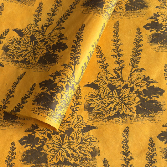A Toile de Jouy style drawing of an agapanthus in brown screen-printed by hand on mustard yellow lokta paper.