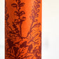 Nepalese handmade decorative lokta paper sheet with a Toile de Jouy style pattern of an agapanthus flower in burgundy screen printed on an orange lokta paper. close-up