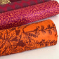 Nepalese handmade decorative lokta paper sheet with a Toile de Jouy style pattern of an agapanthus flower in burgundy screen printed on an orange lokta paper. Rolled