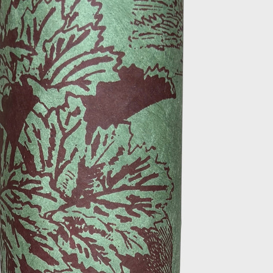 A Toile de Jouy style drawing of an agapanthus in aubergine screen-printed by hand on green lokta paper. close up