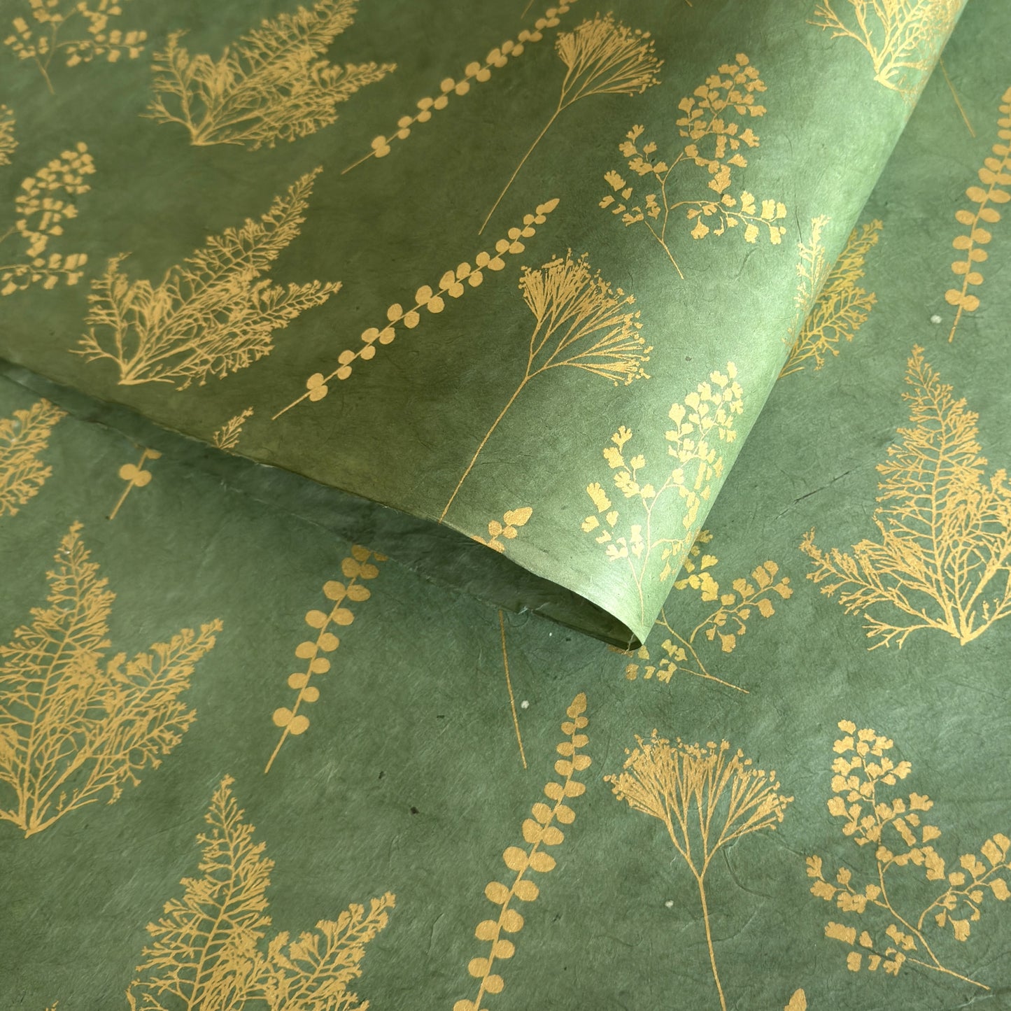 Nepalese handmade decorative lokta paper sheet with gold leaves screen printed on a green lokta paper