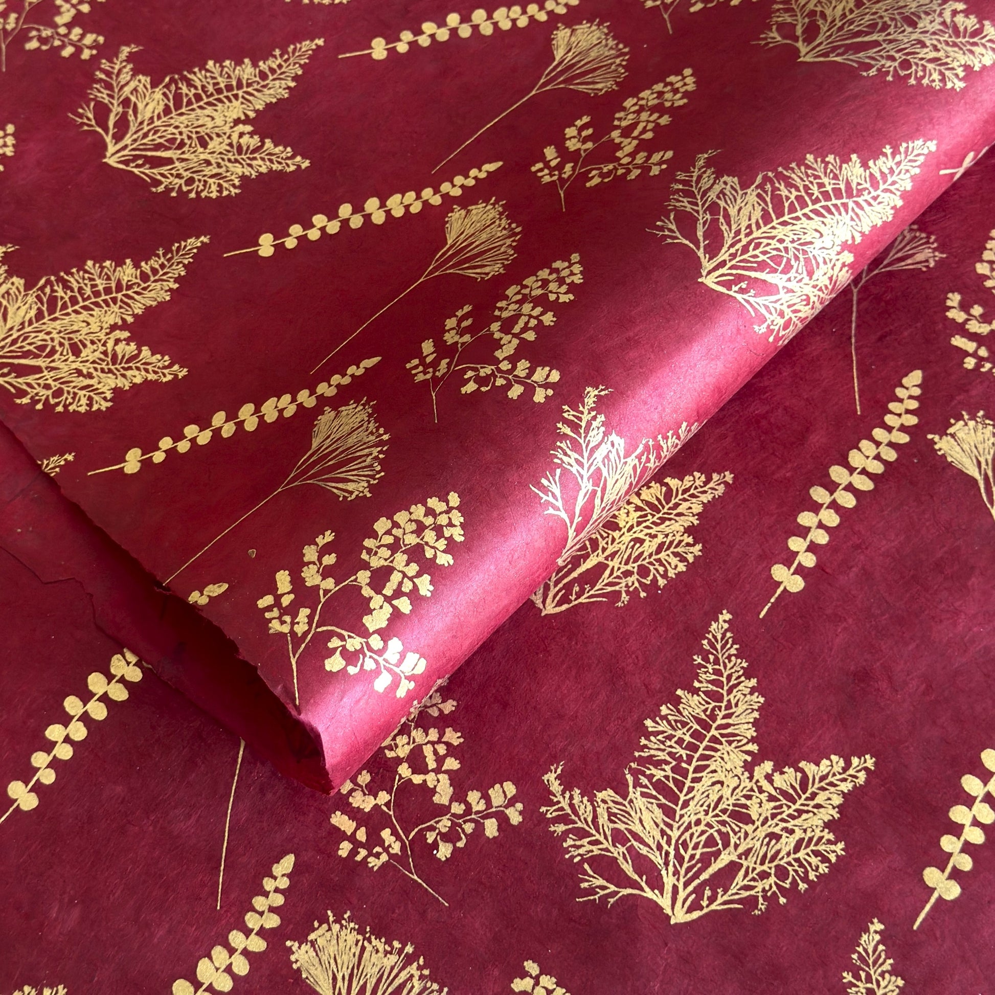 Nepalese handmade decorative lokta paper sheet with gold leaves screen printed on a burgundy red lokta paper