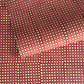 a sheet of Nepalese batik lokta paper in coral rose colour with a repeat white dot design. 