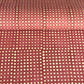 a sheet of Nepalese batik lokta paper in coral rose colour with a repeat white dot design. 