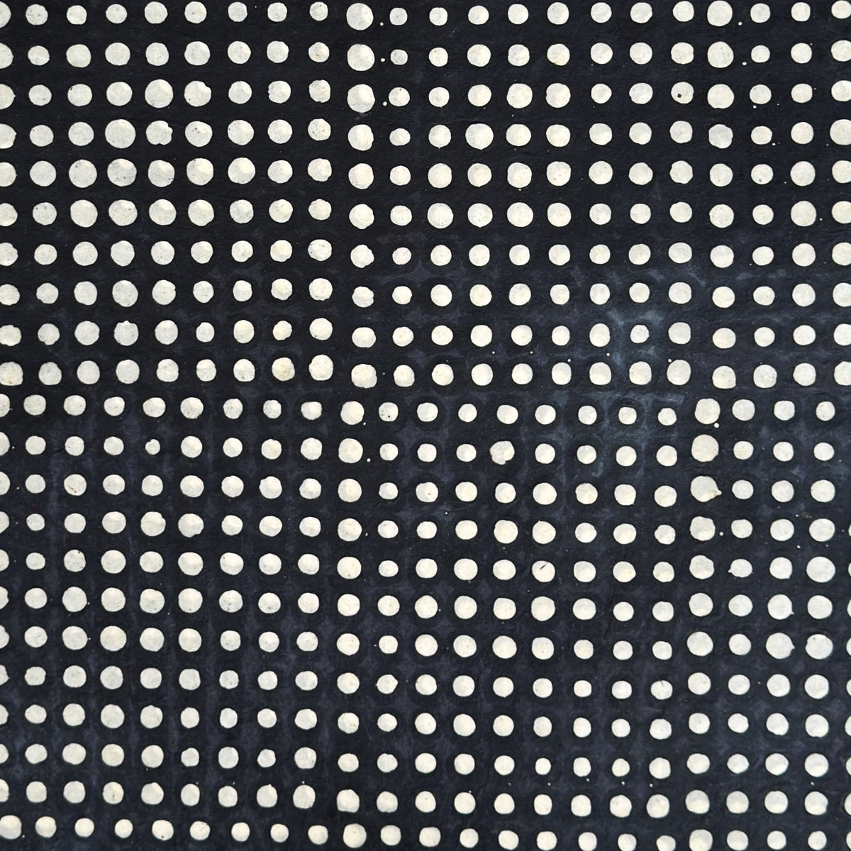 a sheet of black batik dyed Nepalese lokta paper with repeat design of white dots.  