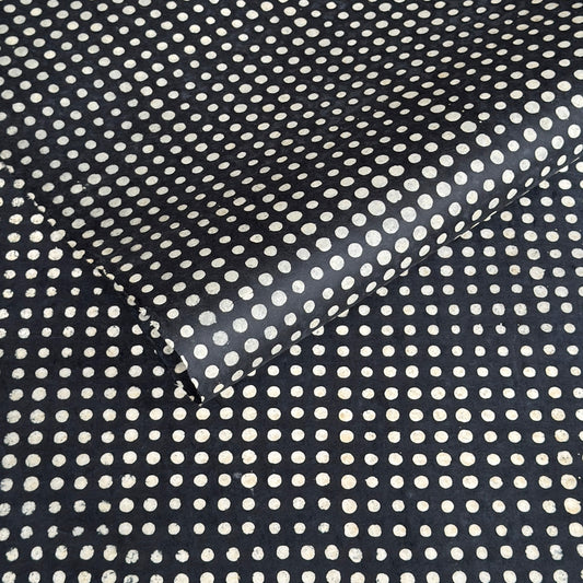 a sheet of black batik dyed Nepalese lokta paper with repeat design of white dots.  Pictured lightly folded