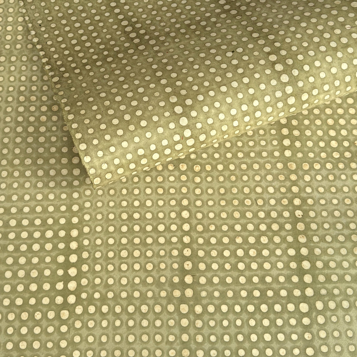 a sheet of Nepalese batik lokta paper in sage green with a repeat white dot design. 