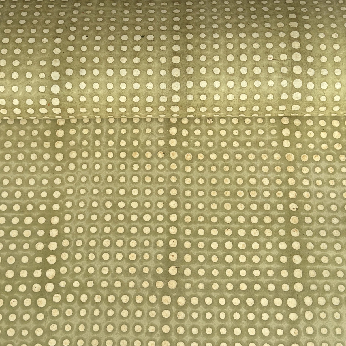 a sheet of Nepalese batik lokta paper in sage green with a repeat white dot design. 