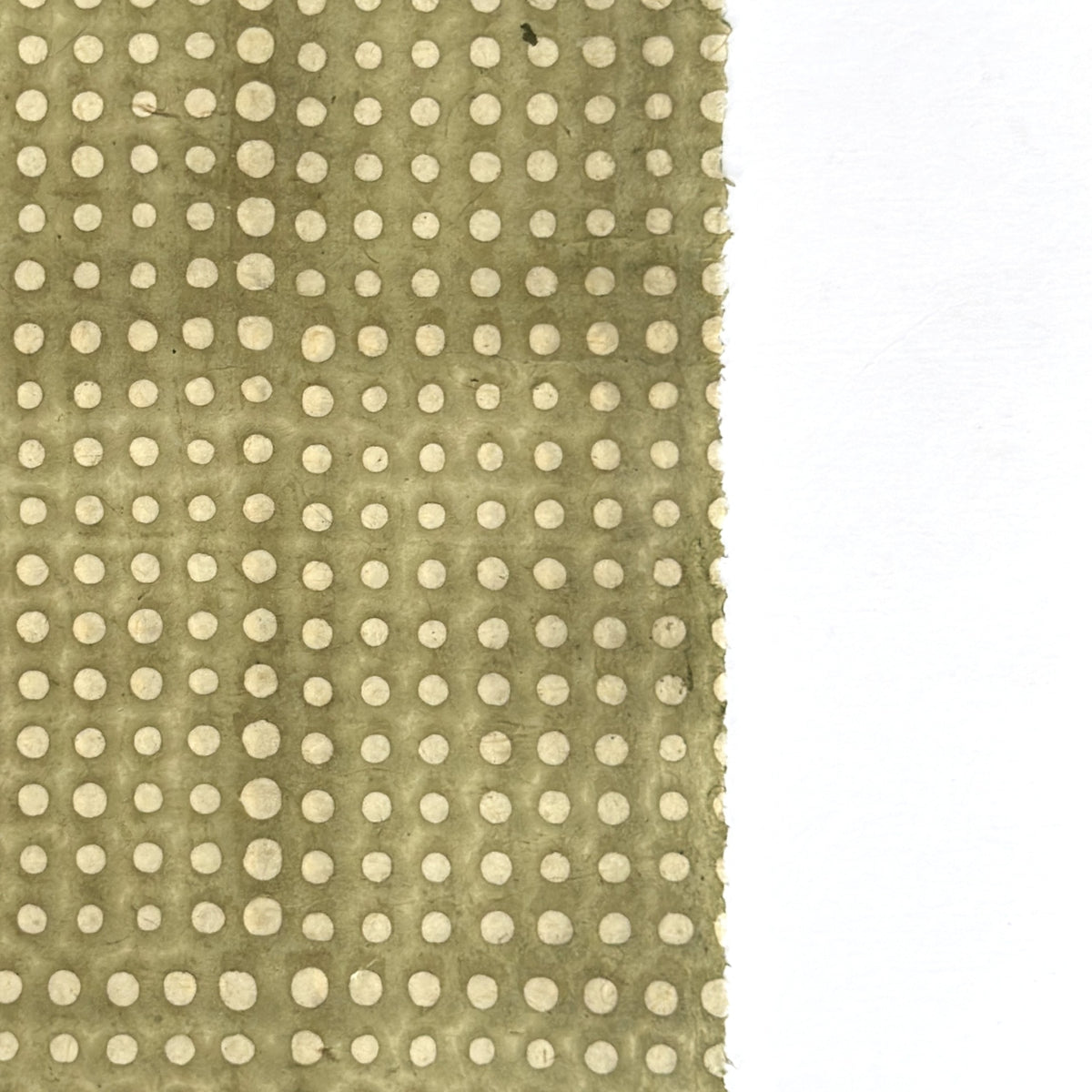 a sheet of Nepalese batik lokta paper in sage green with a repeat white dot design. close up