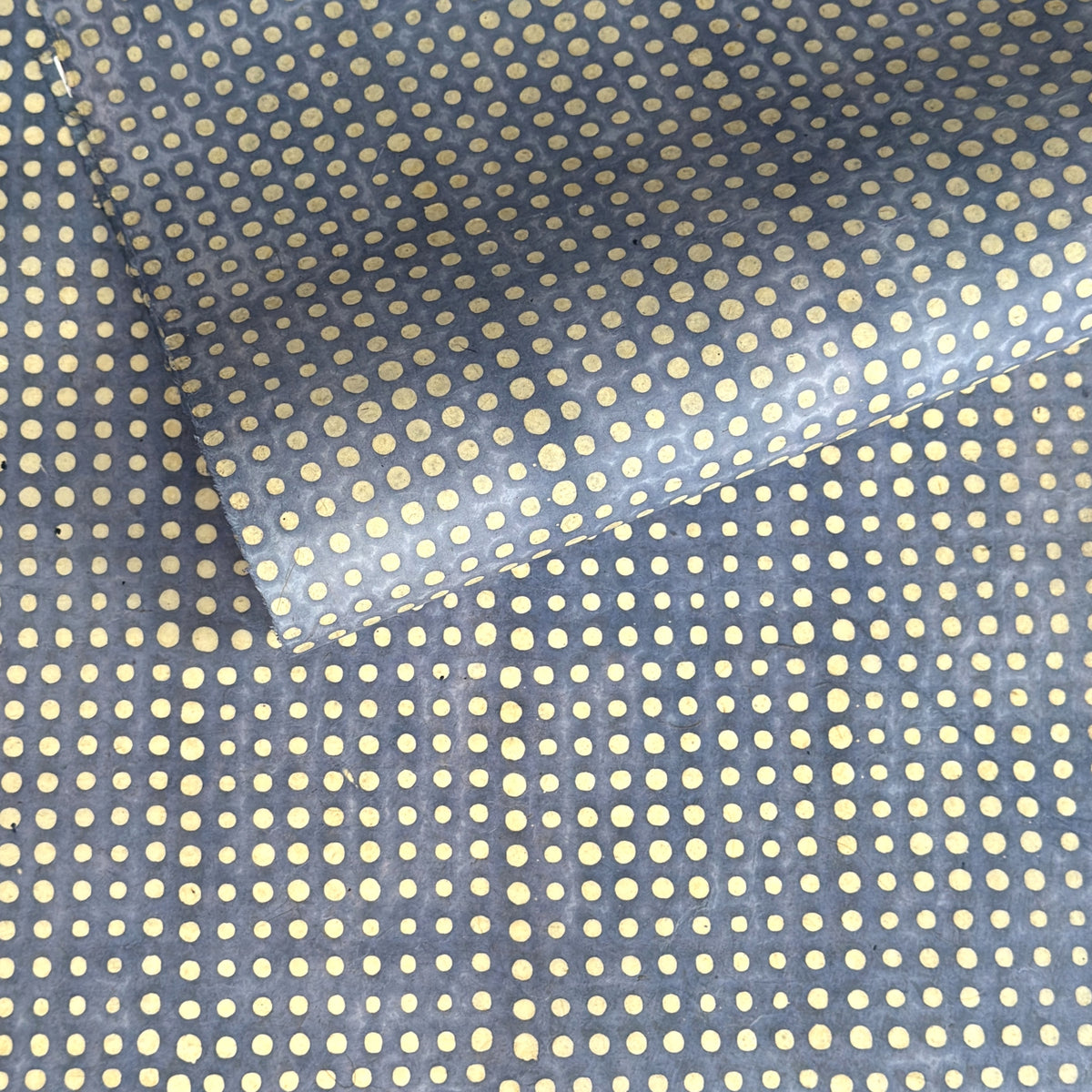 a sheet of Nepalese batik lokta paper in sky blue with a repeat white dot pattern. 