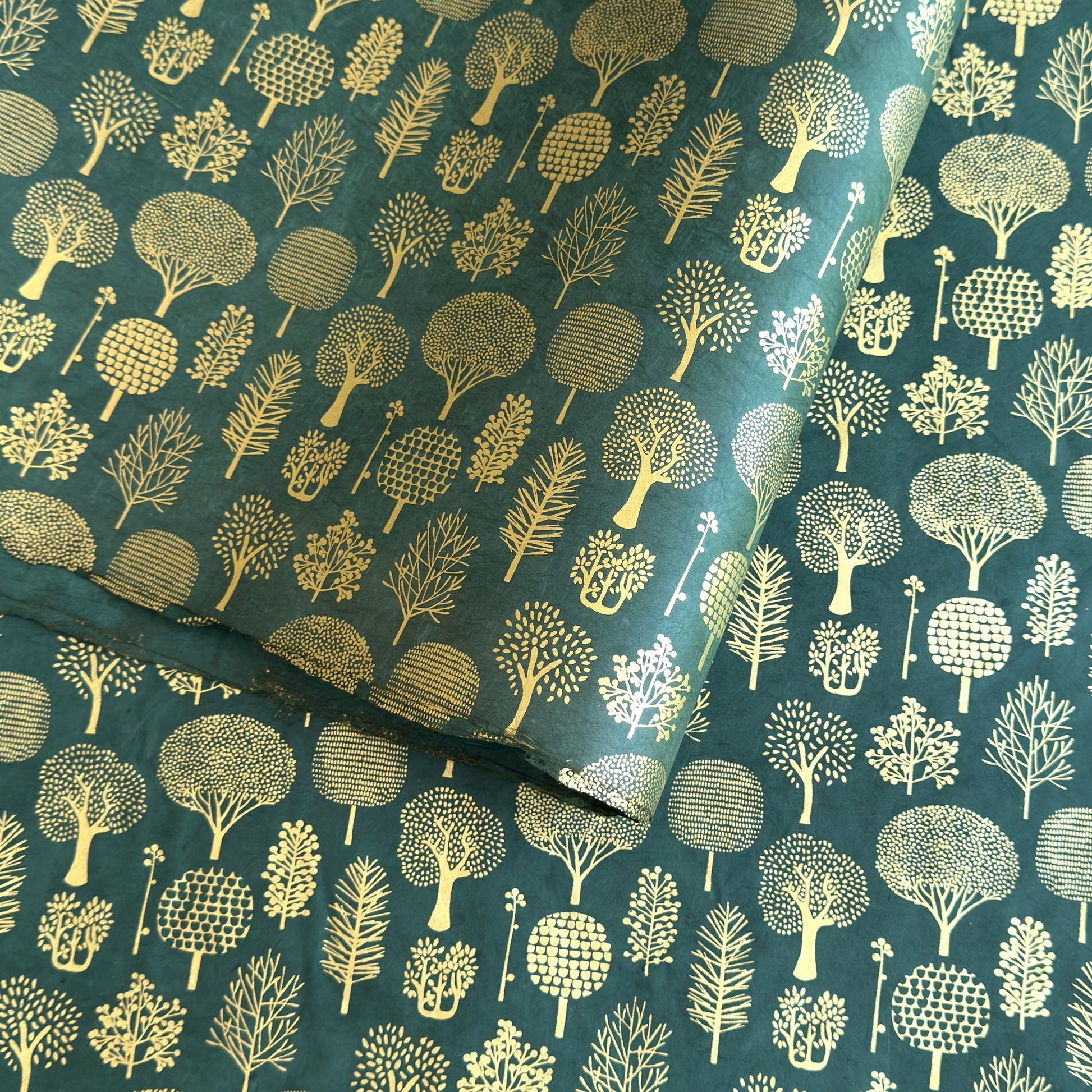 Nepalese handmade decorative lokta paper sheet with gold trees screen printed on a dark green lokta paper.