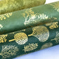 Nepalese handmade decorative lokta paper sheet with gold trees screen printed on a dark green lokta paper. Rolled alongside other designs