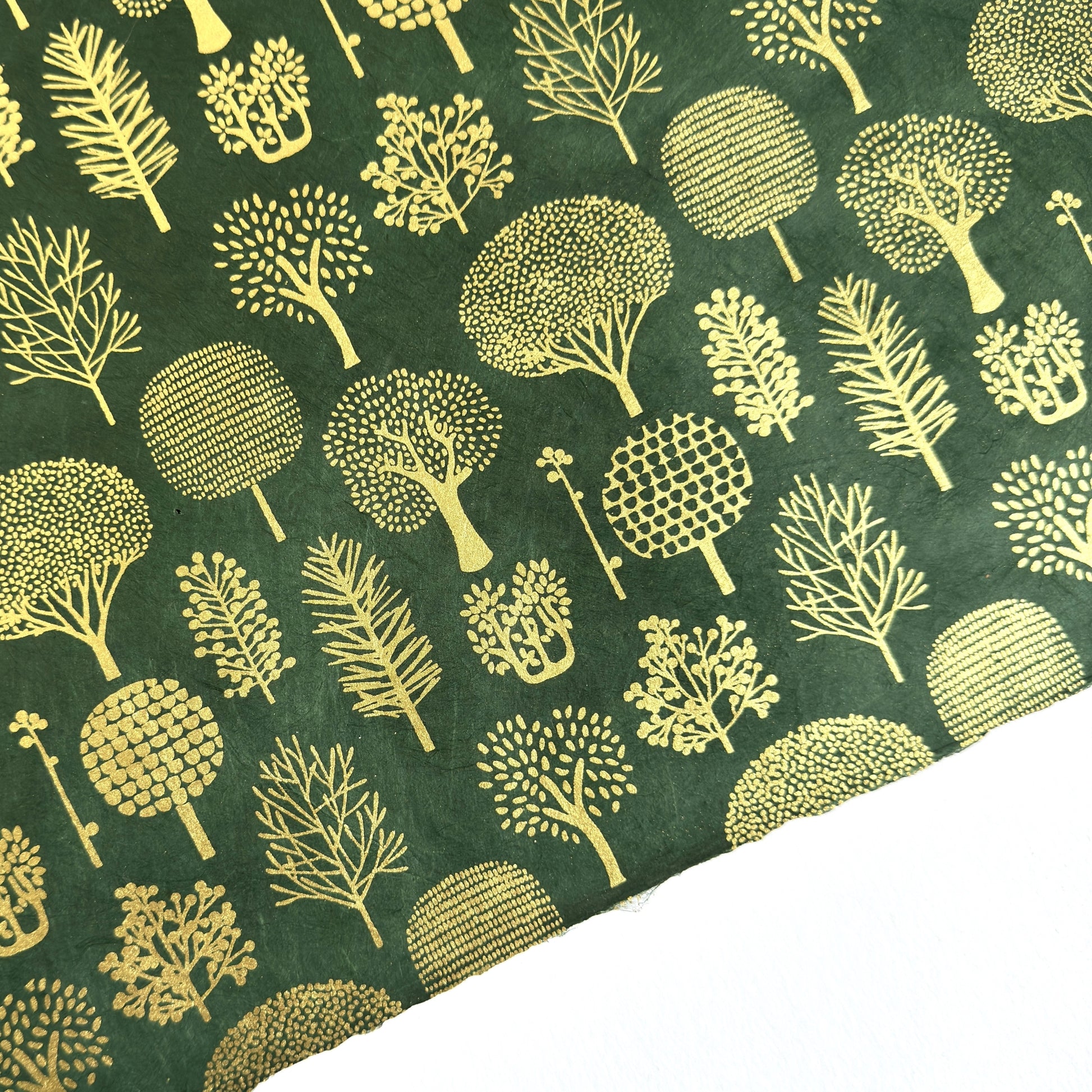 Nepalese handmade decorative lokta paper sheet with gold trees screen printed on a dark green lokta paper. 