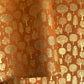 a sheet of screen printed Nepalese lokta paper in terracotta brown with gold trees.  The sheet is pictured lightly folded to show the gold of the trees and the deckled edge of the paper.