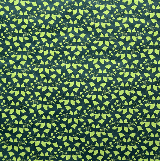 a sheet of lokta paper with a green abstract gingko design on dark green paper