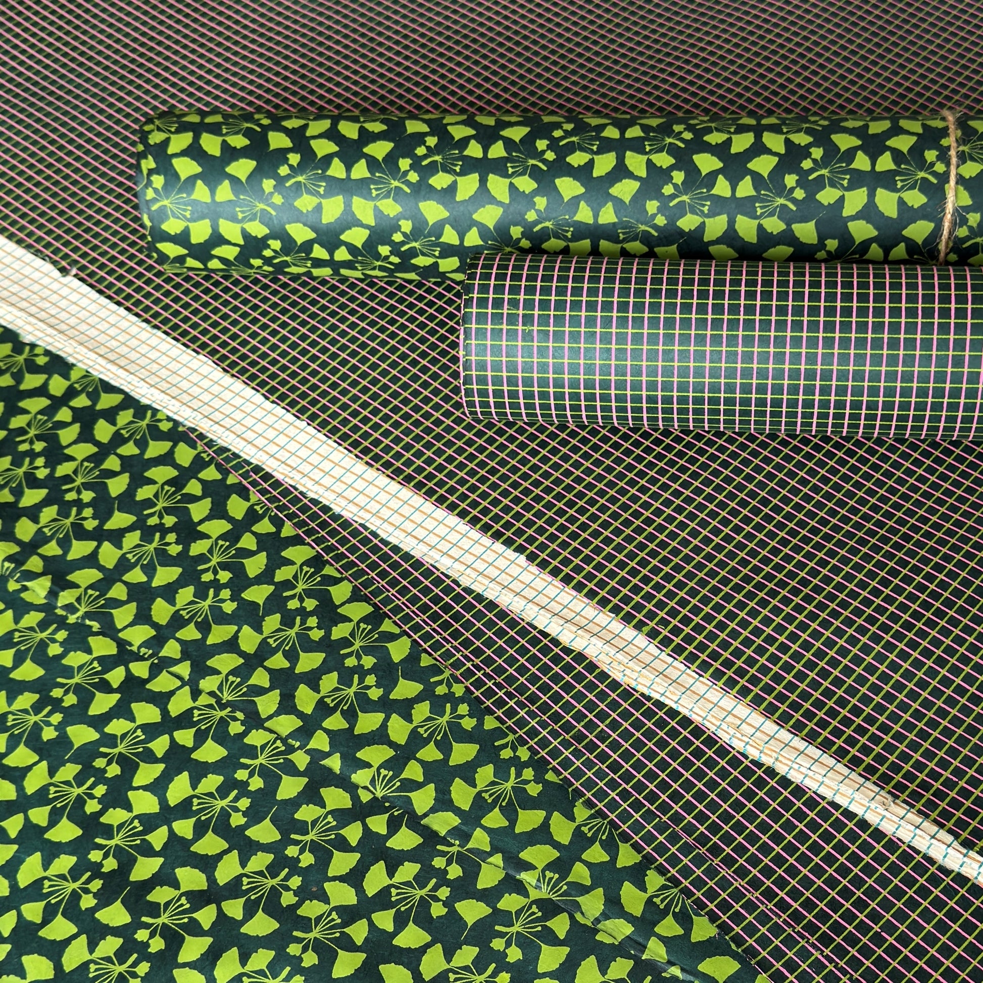 a sheet of lokta paper with a green abstract gingko design on dark green paper.  Pictured with other designs