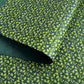 a sheet of lokta paper with a green abstract gingko design on dark green paper