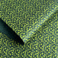 a sheet of lokta paper with a green abstract gingko design on dark green paper