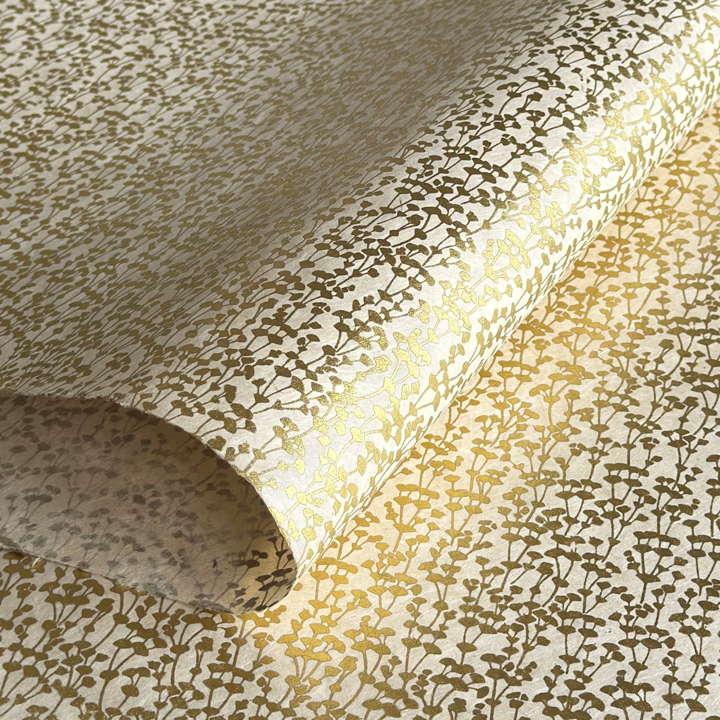 nepalese hand printed lokta paper with a small gold abstract gingko design on white lokta paper