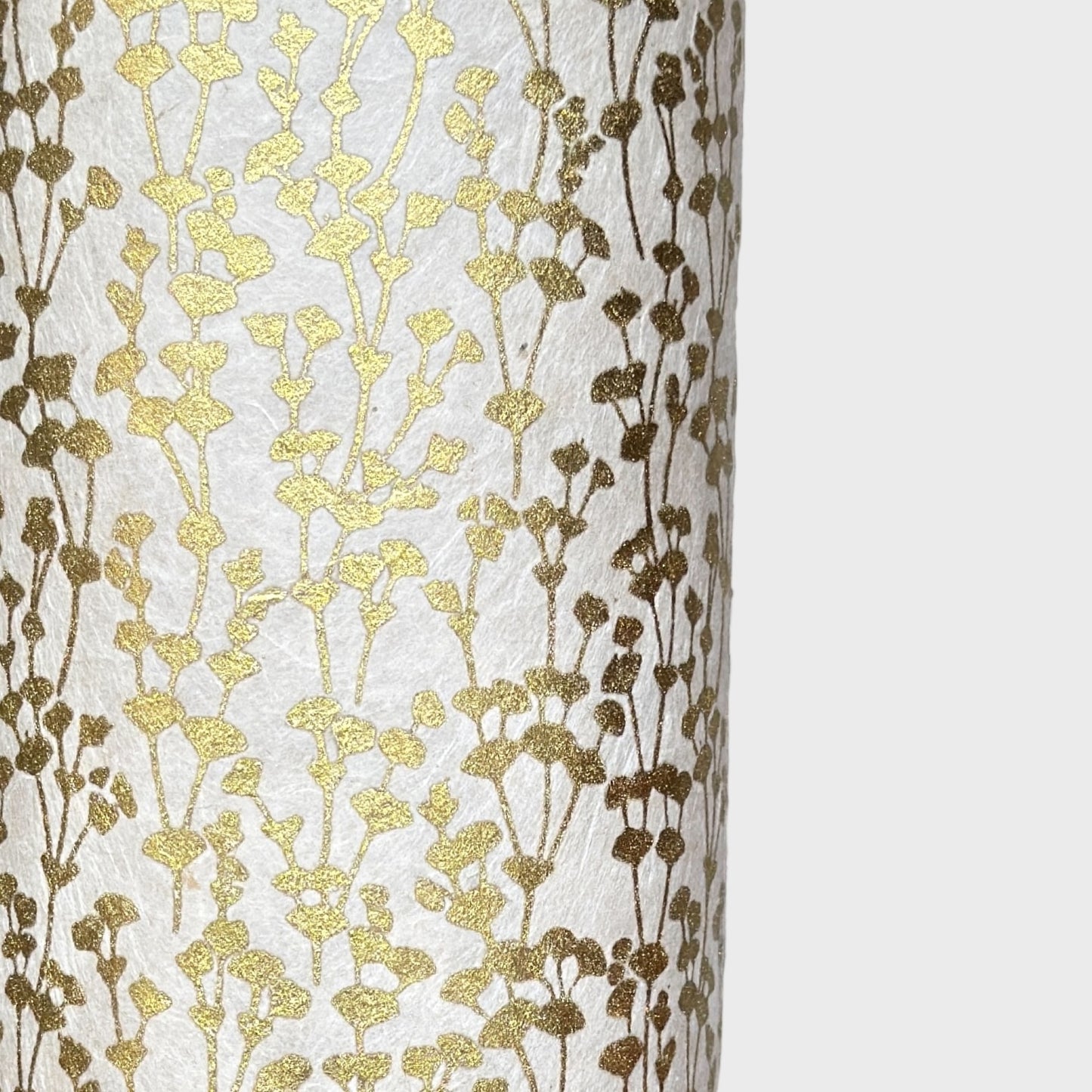 nepalese hand printed lokta paper with a small gold abstract gingko design on white lokta paper. close up