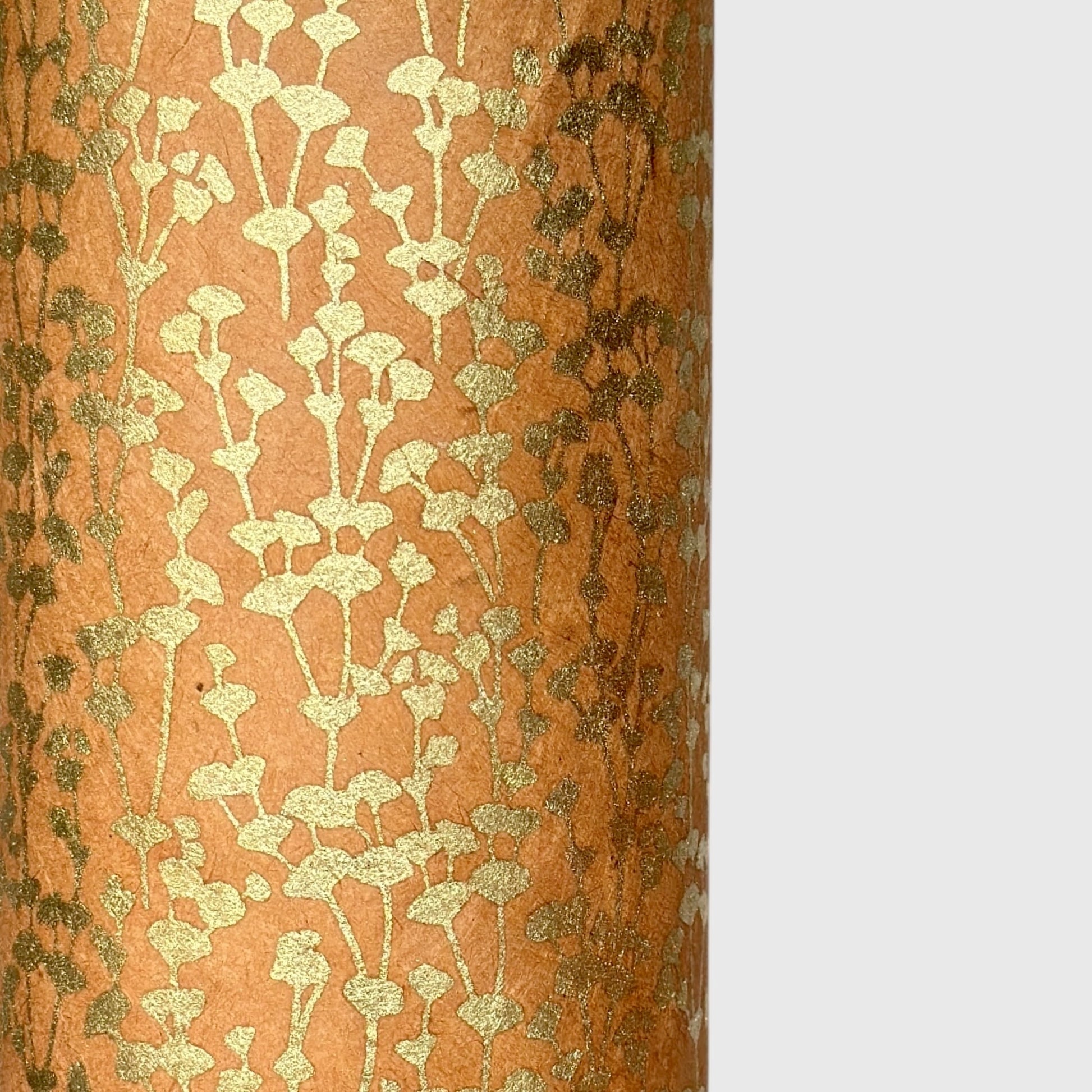 nepalese hand printed lokta paper with a small gold abstract gingko design on tan lokta paper. close up