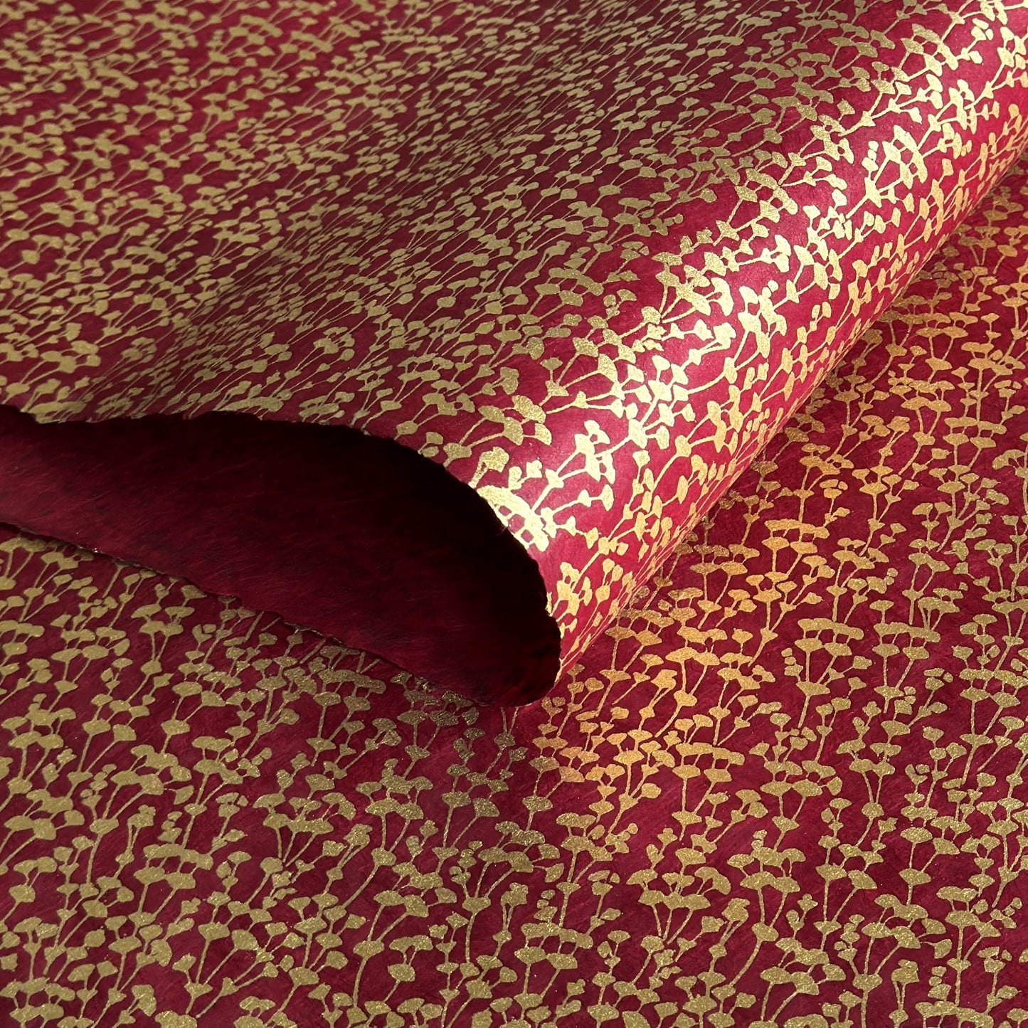 nepalese hand printed lokta paper with a small gold abstract gingko design on red lokta paper