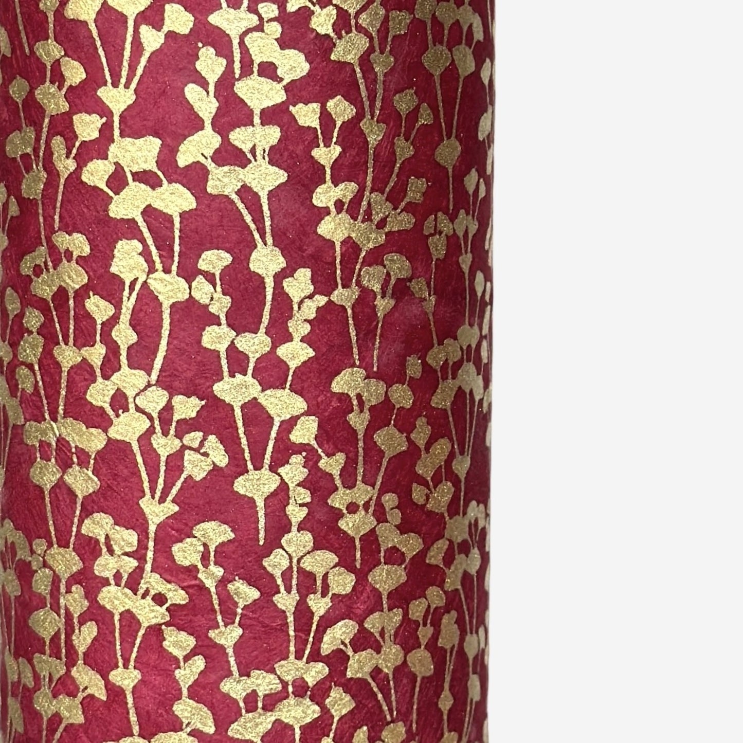 nepalese hand printed lokta paper with a small gold abstract gingko design on red lokta paper. close up