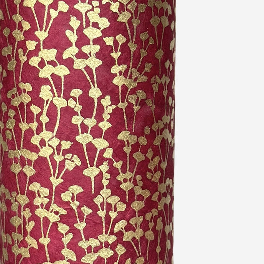 nepalese hand printed lokta paper with a small gold abstract gingko design on red lokta paper. close up