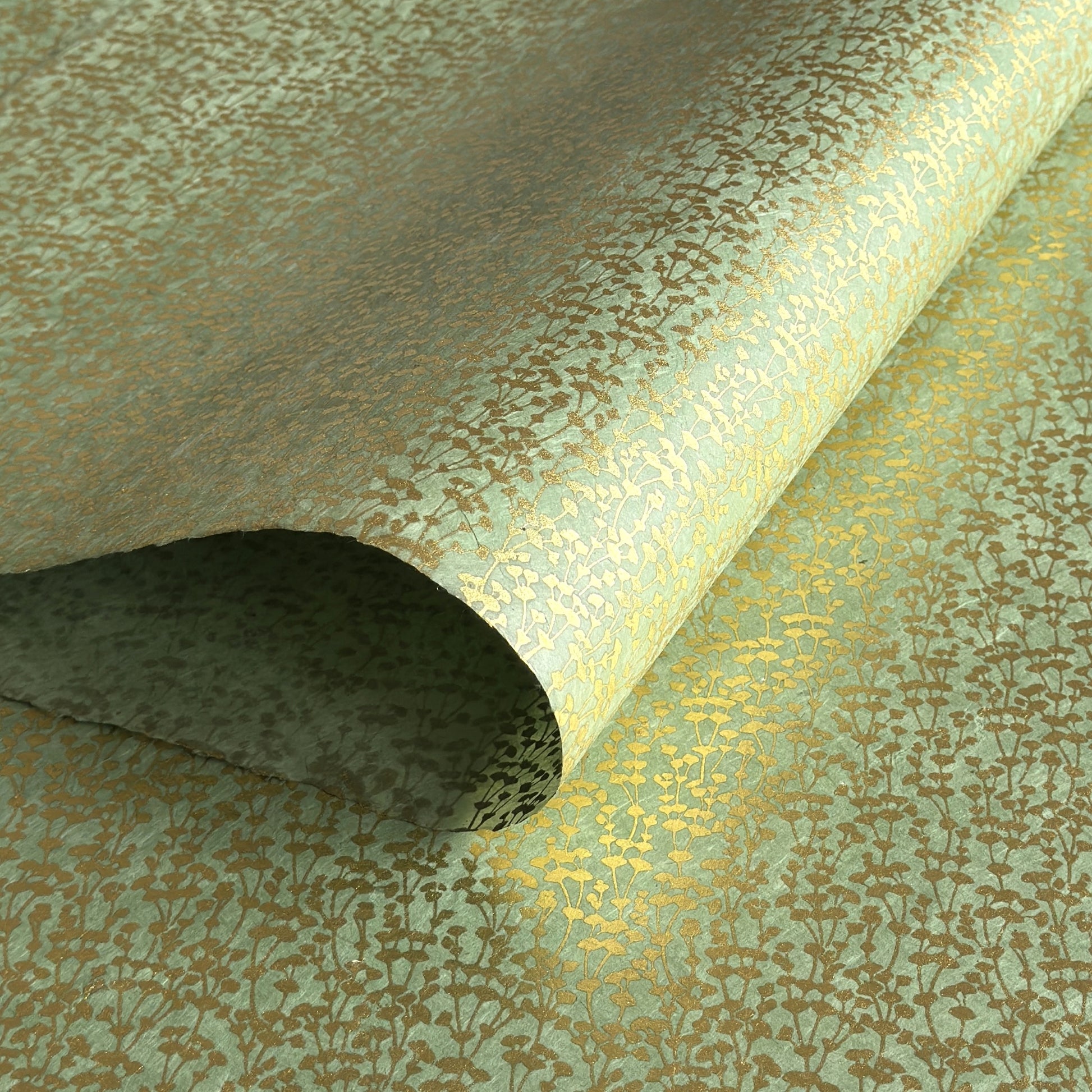 nepalese hand printed lokta paper with a small gold abstract gingko design on green lokta paper