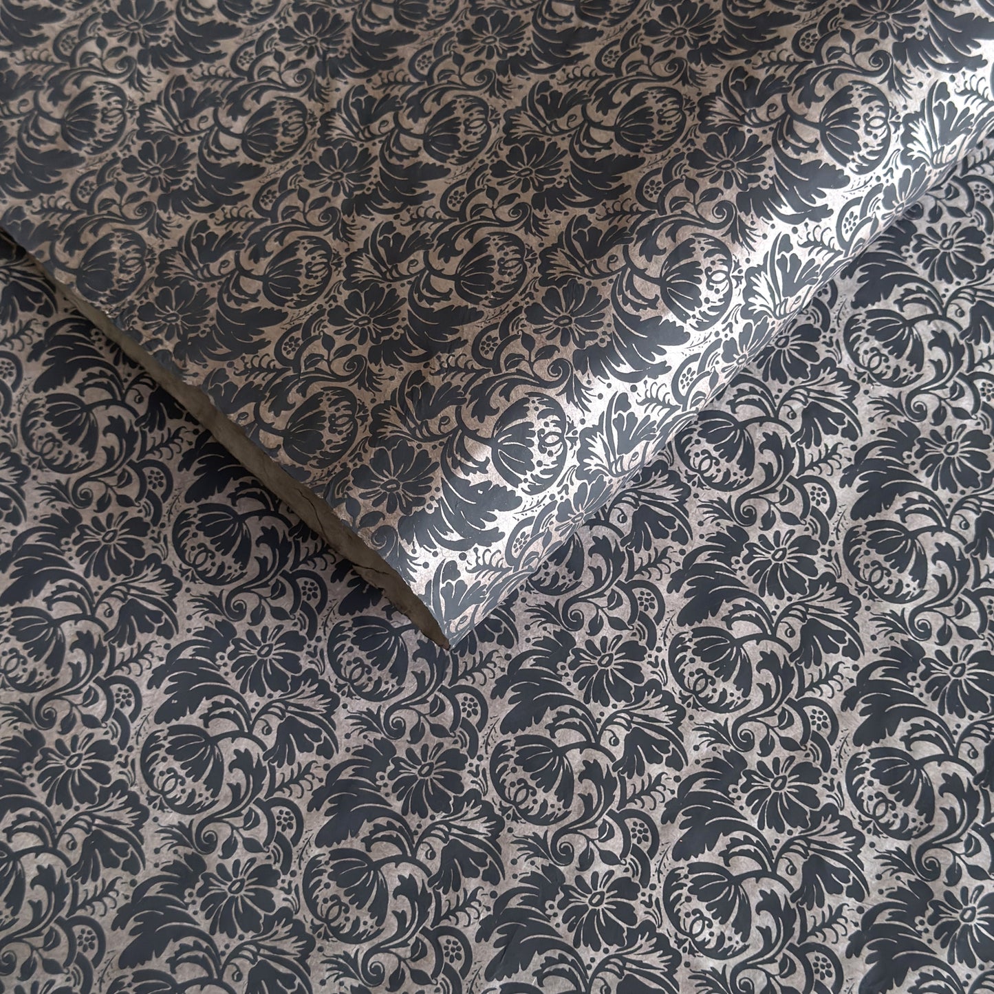 Nepalese handmade decorative lokta paper sheet with a black floral pattern screen printed on a dark taupe lokta paper.