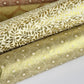 Nepalese handmade decorative lokta paper sheet with a gold metallic repeat floral pattern screen printed on an ivory lokta paper. Pictured rolled with other designs