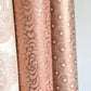 Nepalese handmade decorative lokta paper sheet with a metallic copper floral print screen printed on a blush pink lokta paper. Pictured rolled with other designs of paper.