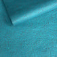 a sheet of Nepalese lokta paper screen printed with a repeat floral pattern in dark grey/blue on a bright teal lokta paper