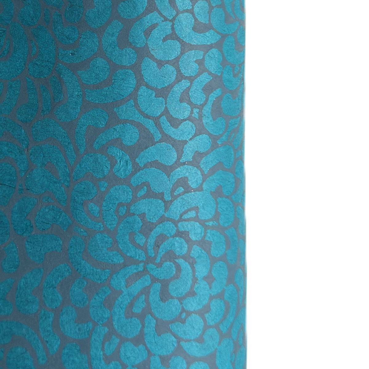 a sheet of Nepalese lokta paper screen printed with a repeat floral pattern in dark grey/blue on a bright teal lokta paper. Close up