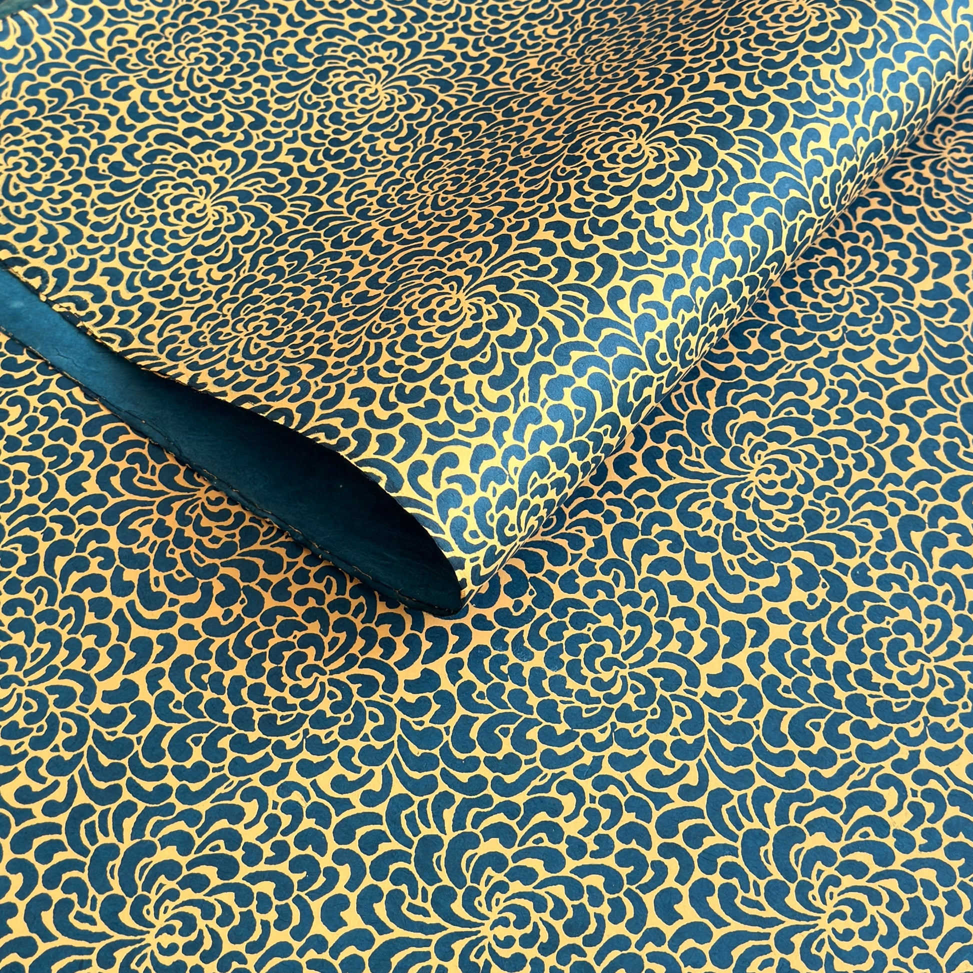 Nepalese handmade decorative lokta paper sheet with a saffron floral print screen printed on a teal lokta paper. 