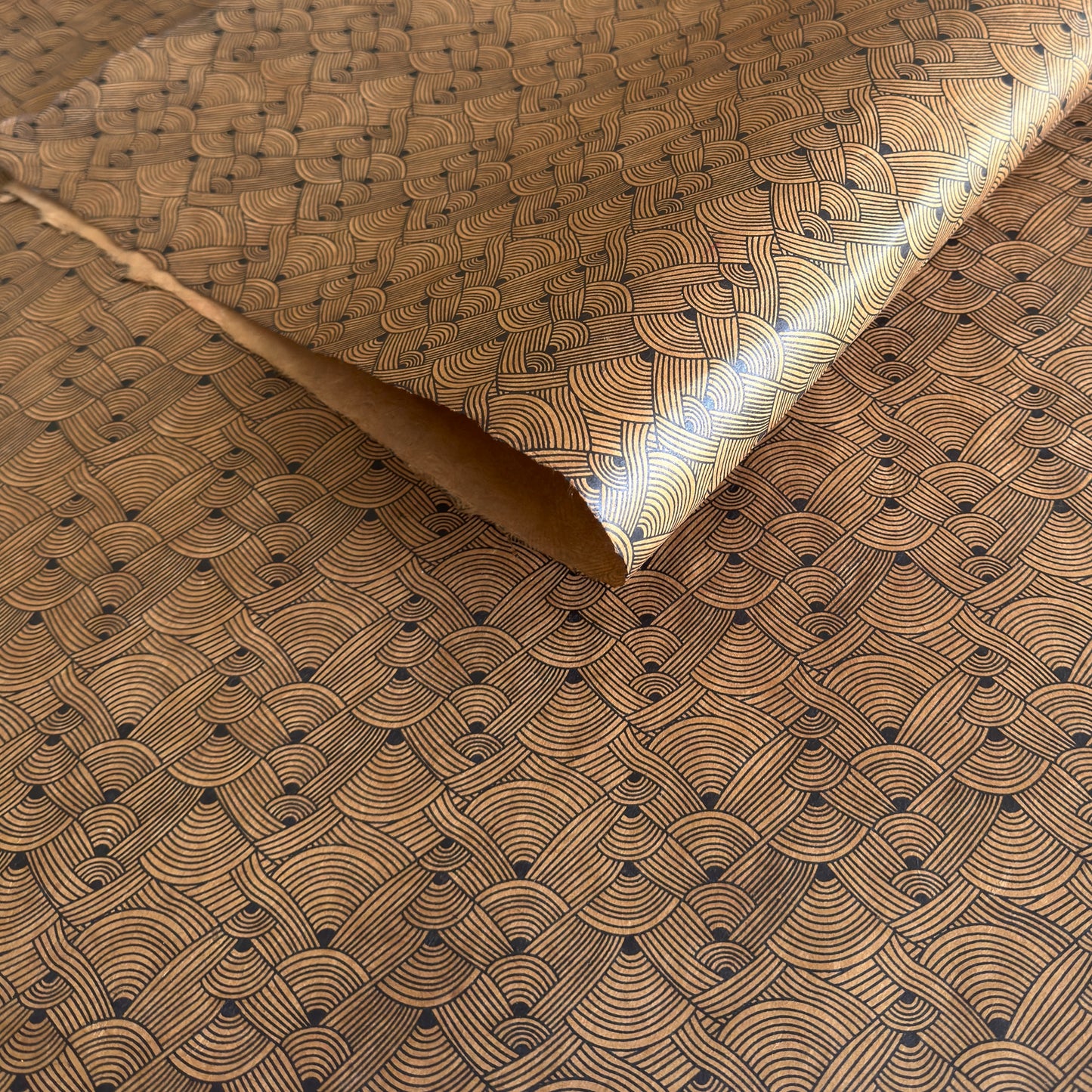 Nepalese handmade decorative lokta paper sheet with a fine lined black knots pattern screen printed on a brown lokta paper.