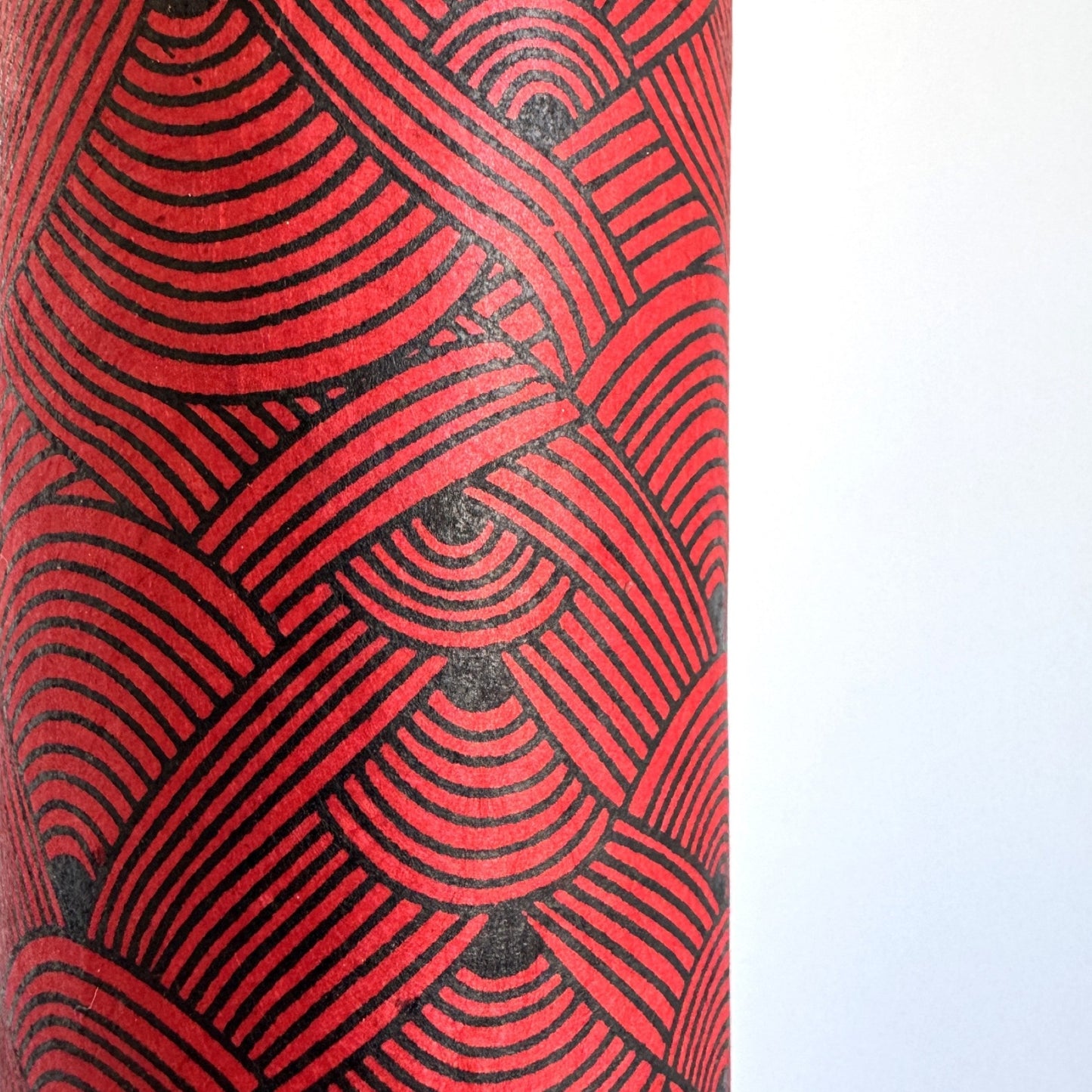 Nepalese handmade decorative lokta paper sheet with a fine lined black knots pattern screen printed on a red lokta paper.