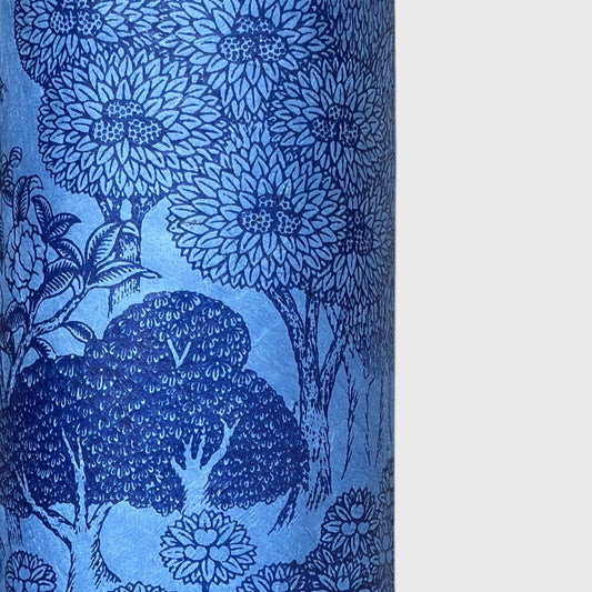 Detailed pattern of trees and flowers in dark blue screen-printed by hand on a blue lokta paper. Close up