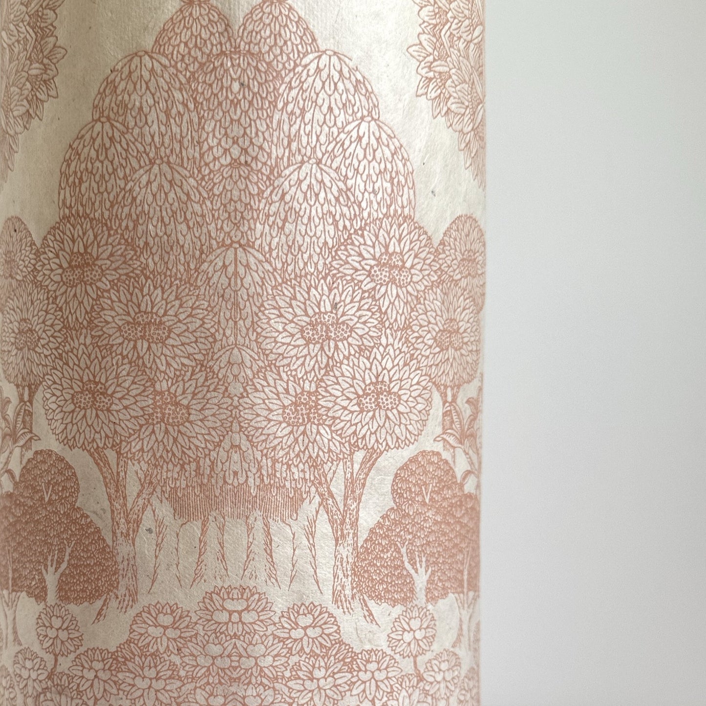 Nepalese handmade decorative lokta paper sheet with a detailed design of trees and flowers in blush pink screen printed on an ivory lokta paper.