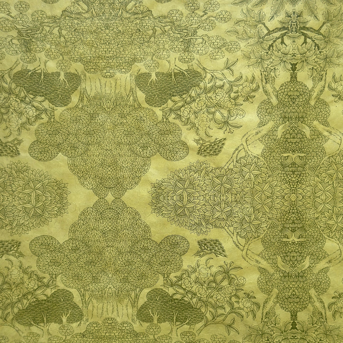 Nepalese handmade decorative lokta paper sheet with a detailed design of trees and flowers in dark green screen printed on a green lokta paper.