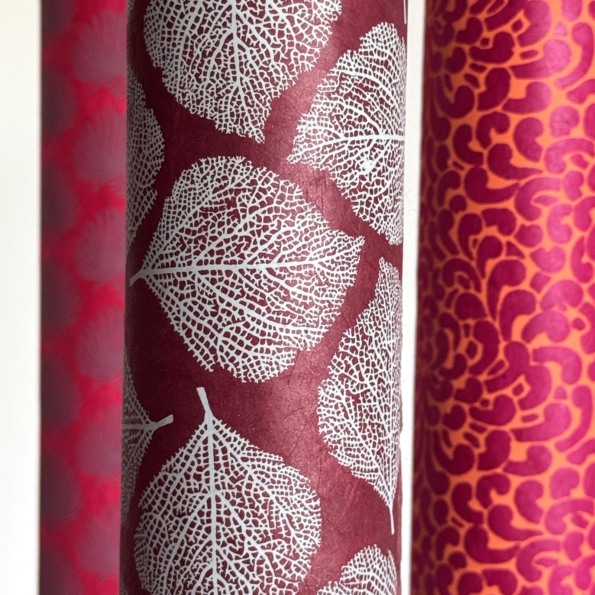 Nepalese handmade decorative lokta paper sheet with a white leaf pattern screen printed on a burgundy lokta paper.