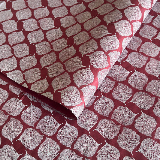 Nepalese handmade decorative lokta paper sheet with a white leaf pattern screen printed on a burgundy lokta paper.