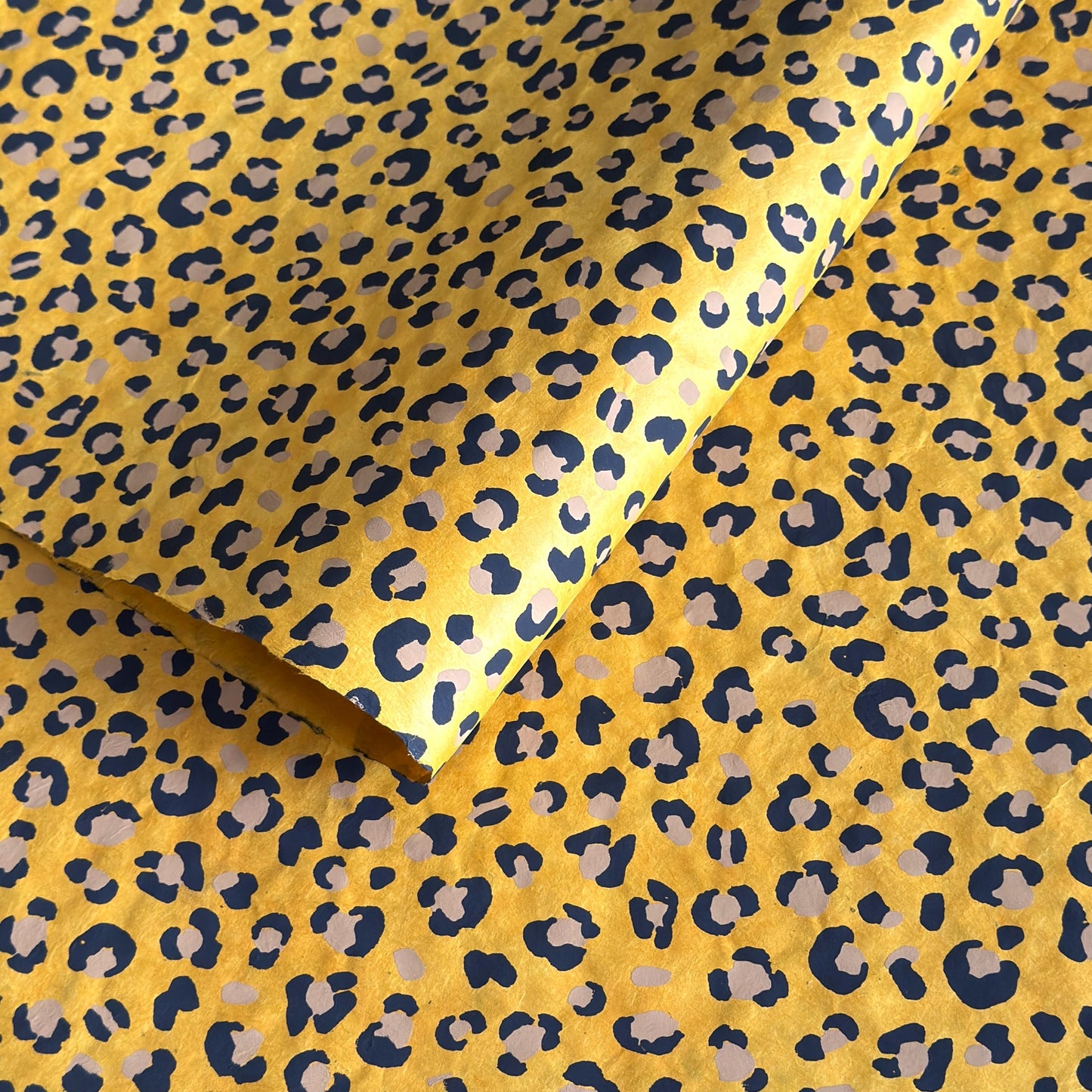 Nepalese handmade decorative lokta paper sheet with an animal print design in two colours, tan and black, screen printed on a yellow lokta paper.