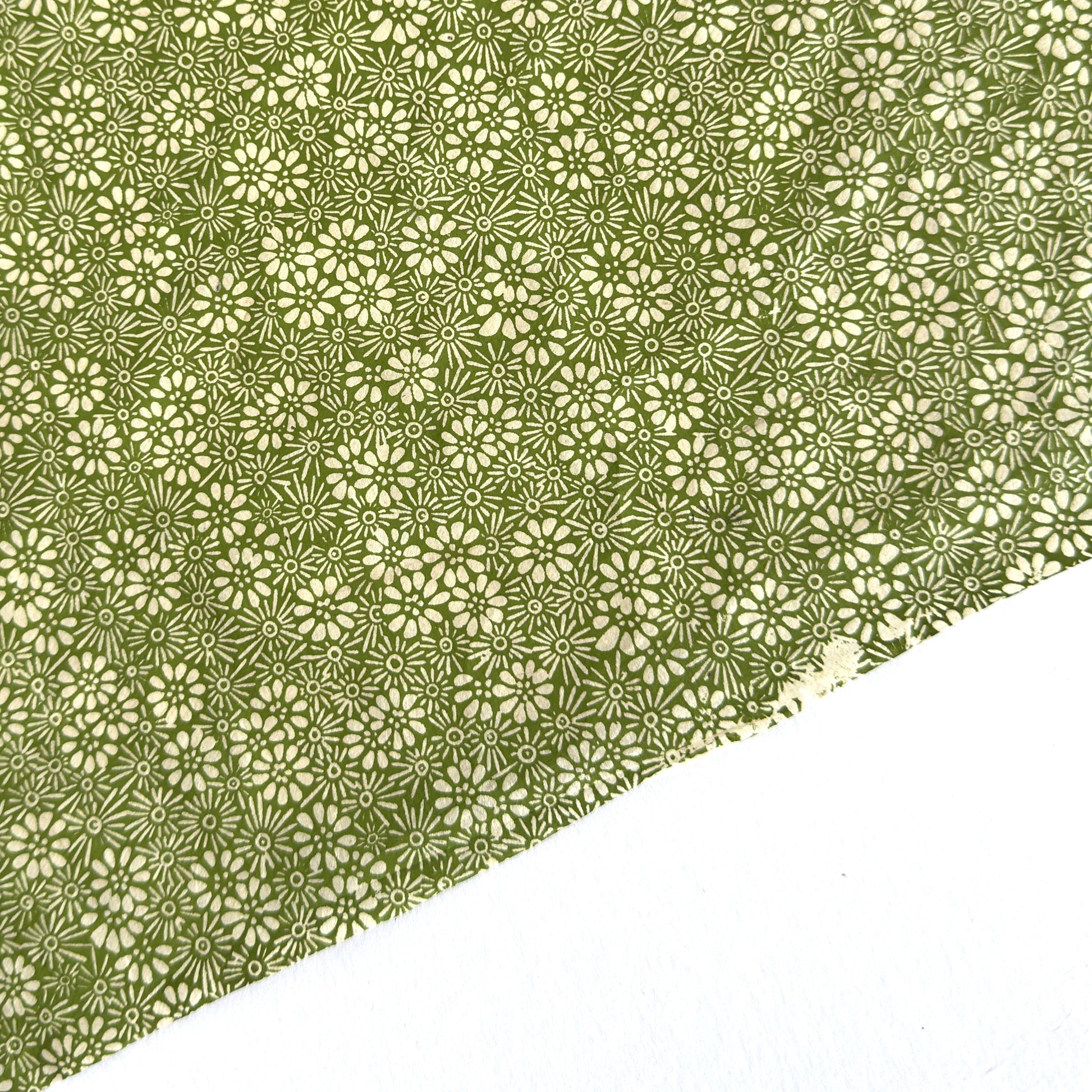 Nepalese handmade decorative lokta paper sheet with a white ditsy floral design screen printed on a green lokta paper.