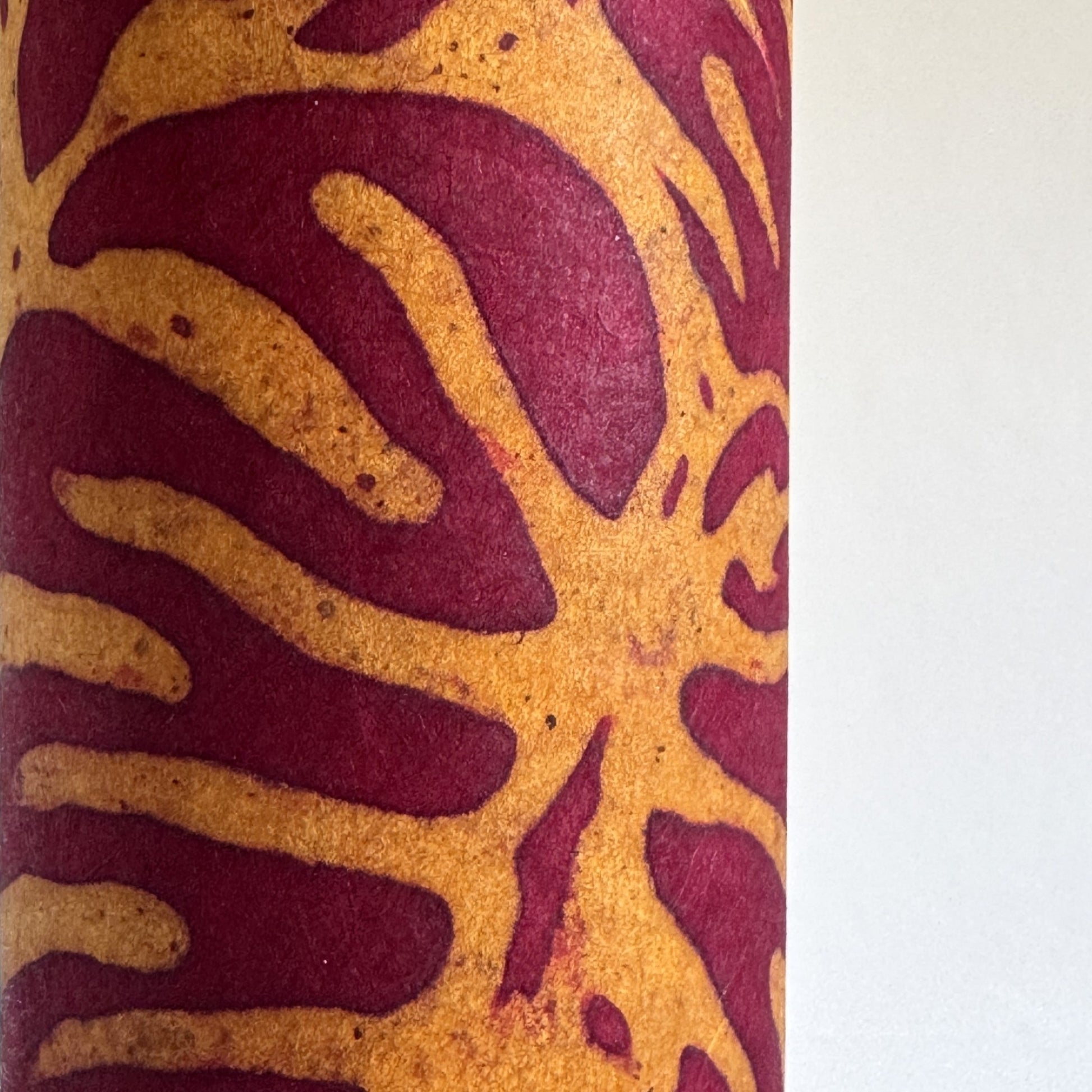 Nepalese handmade decorative lokta paper sheet with a leaf pattern in burgundy red and yellow.  Batik dyed using carved wooden blocks.