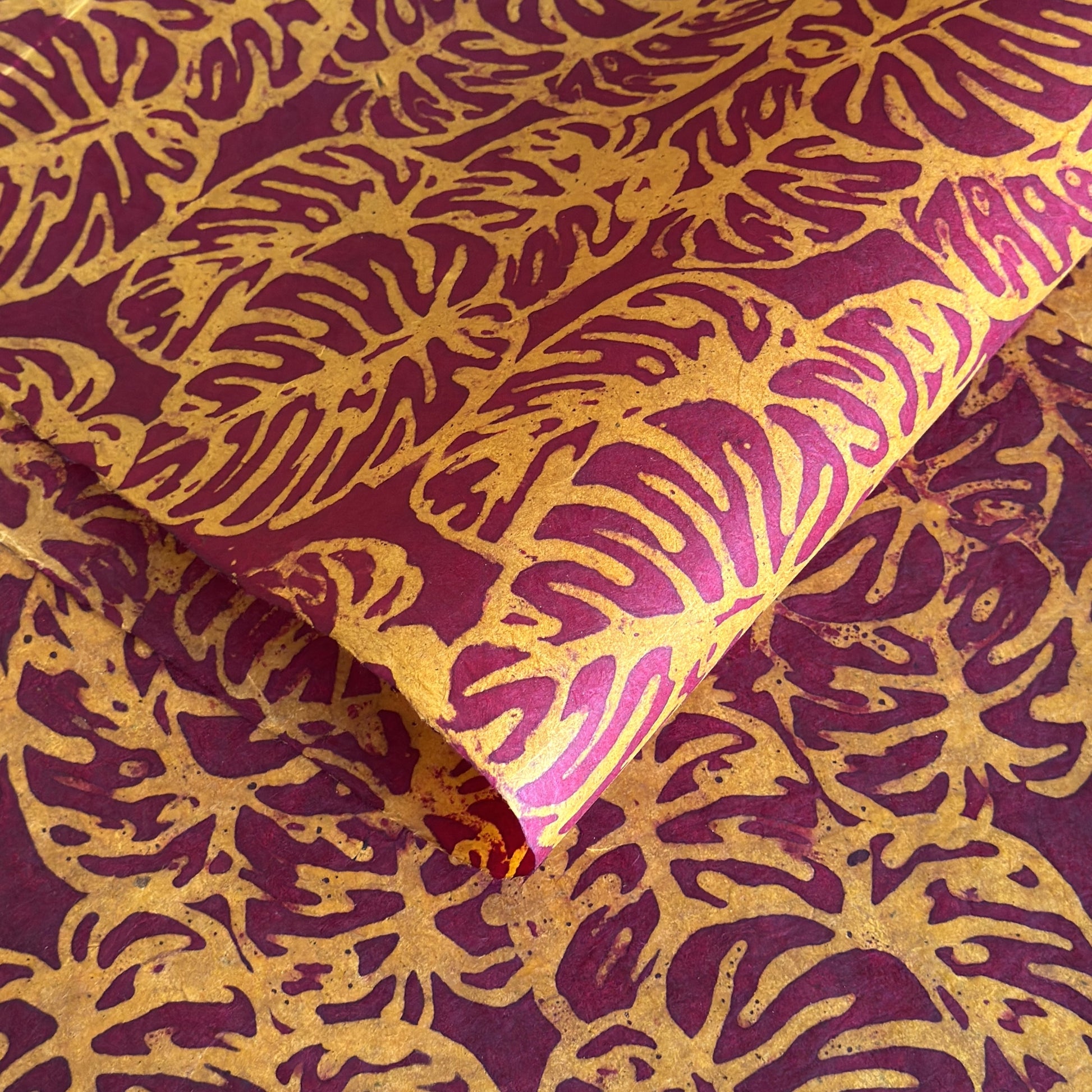 Nepalese handmade decorative lokta paper sheet with a leaf pattern in burgundy red and yellow.  Batik dyed using carved wooden blocks.