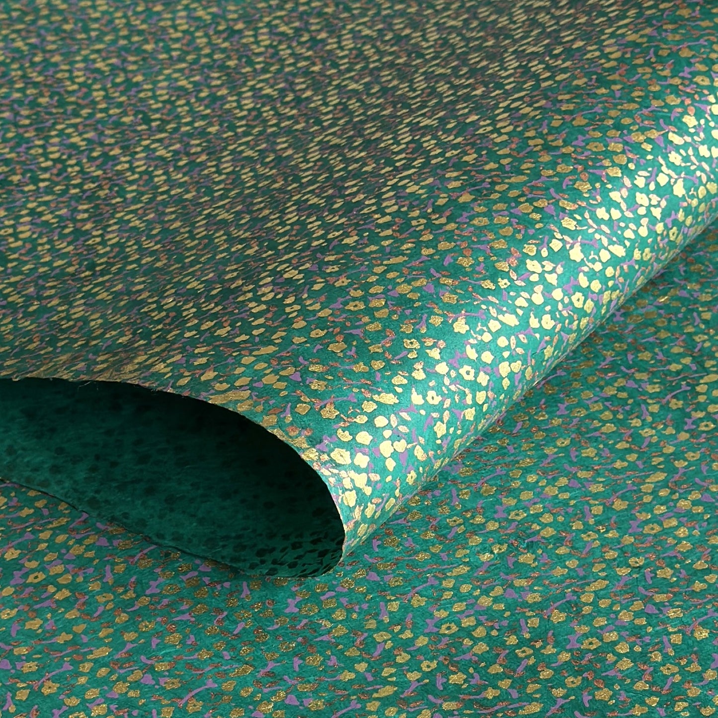 A delicate floral pattern in gold, blush and lilac screen-printed by hand on emerald lokta paper.