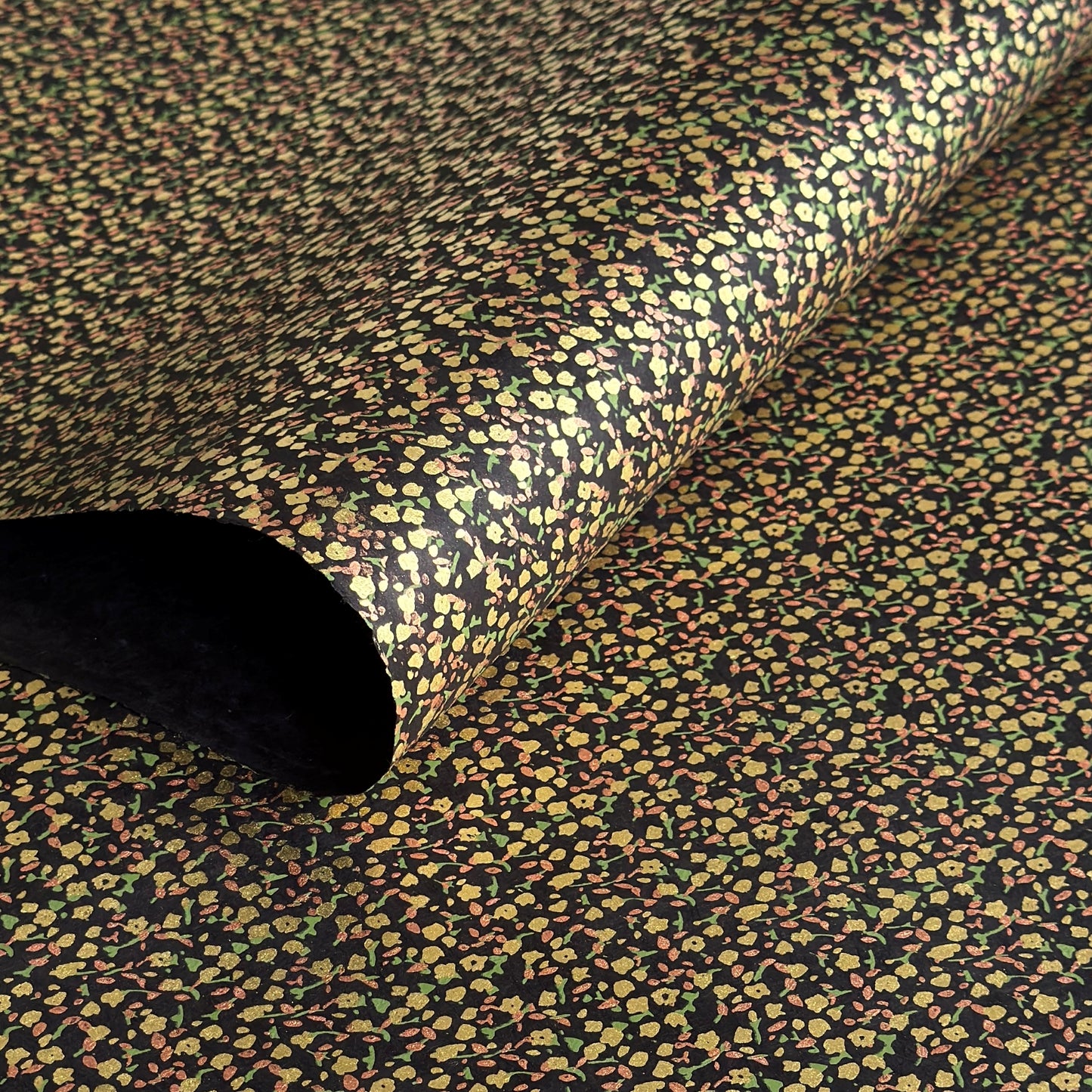 A delicate floral pattern in gold, blush and green screen-printed by hand on black lokta paper.