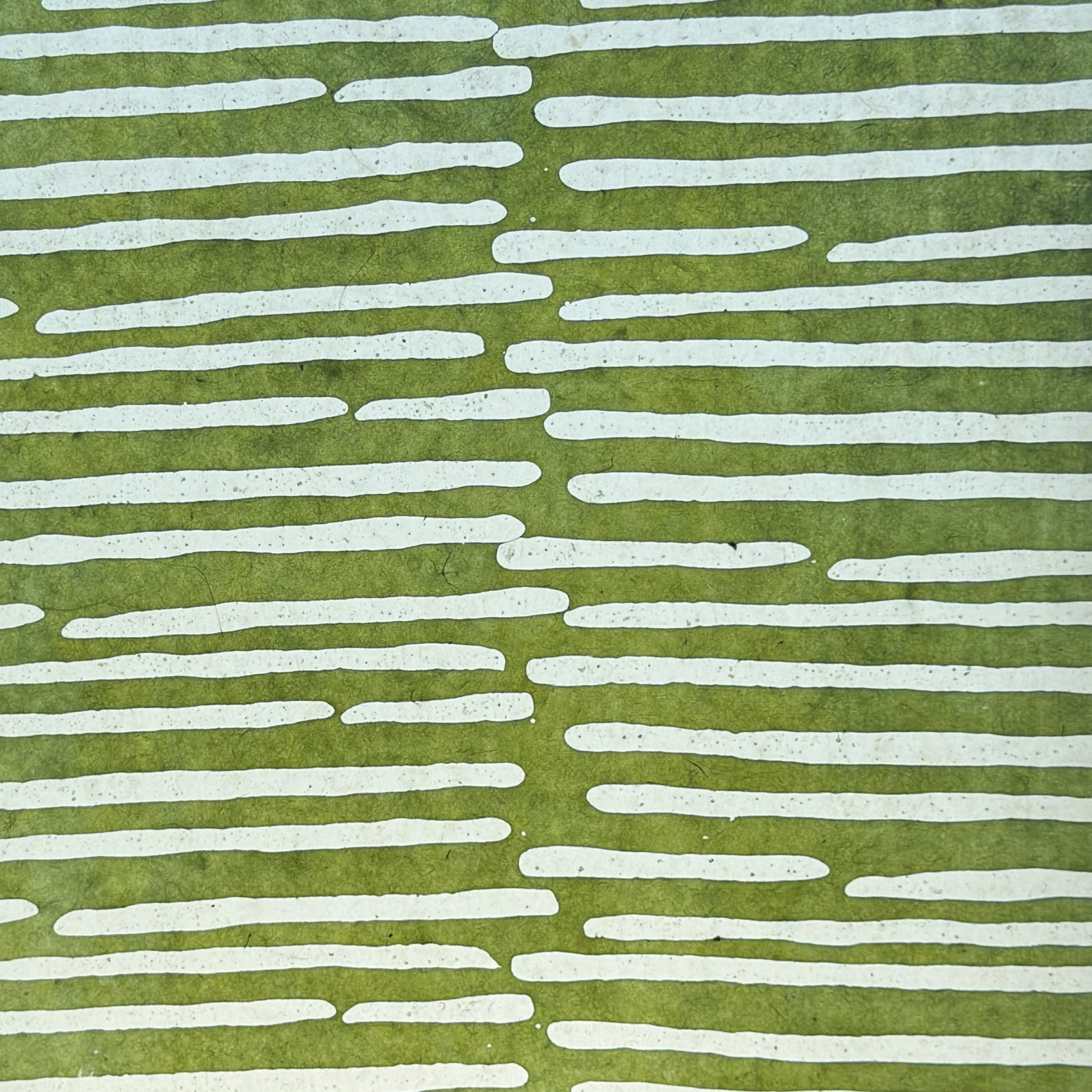 Nepalese handmade decorative lokta paper sheet with a stripe pattern in mossy and white.  Batik dyed using carved wooden blocks. Picture next to light to show the translucent nature